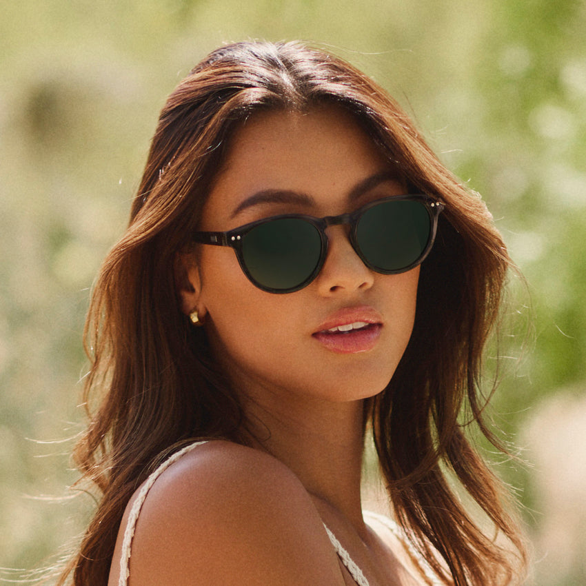 Woman wearing stylish retro round sunglasses with notched keyhole bridge and double rivets outdoors