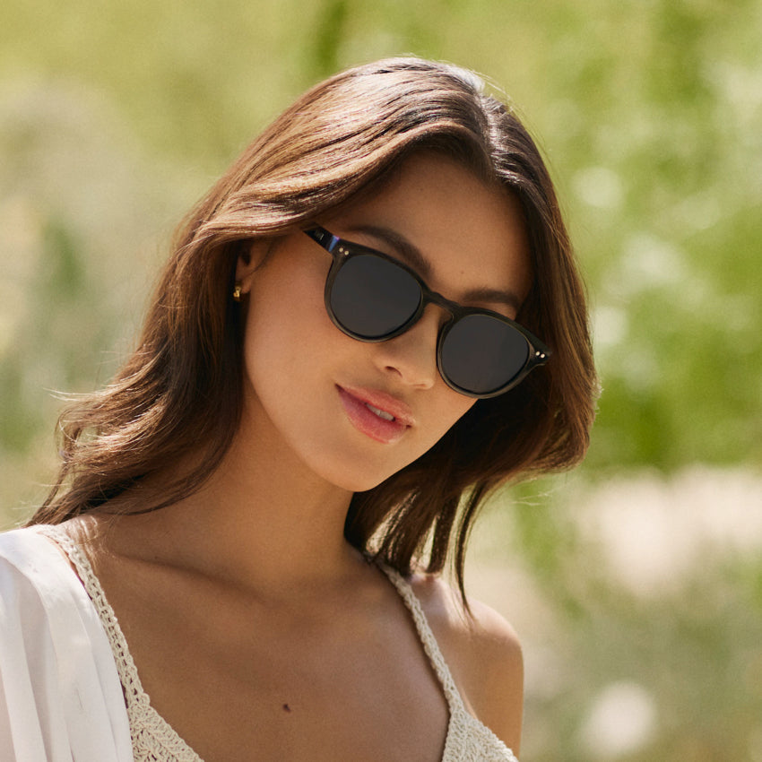 Woman wearing retro round-shaped Tate sunglasses with notched keyhole bridge and double rivets in natural light