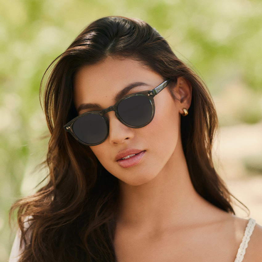Woman wearing stylish round sunglasses with a notched keyhole bridge and double rivets outdoors