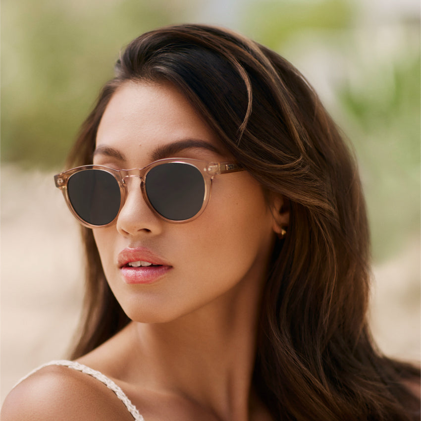 Woman wearing stylish retro round-shaped sunglasses with a notched keyhole bridge and double rivets on frame