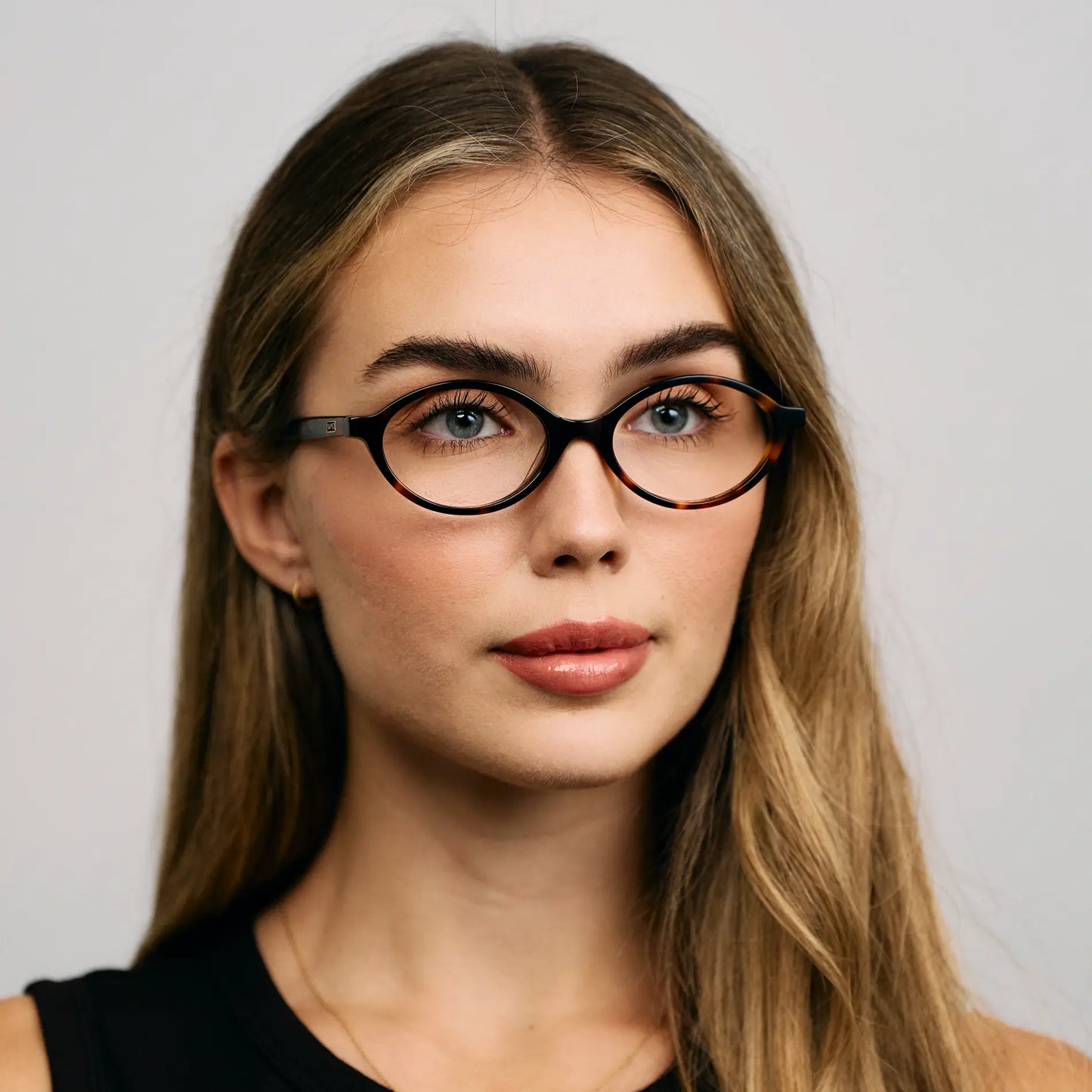 Brown Tortoise || Oval prescription eyeglasses with slim brown tortoise frame worn by woman indoors in natural light
