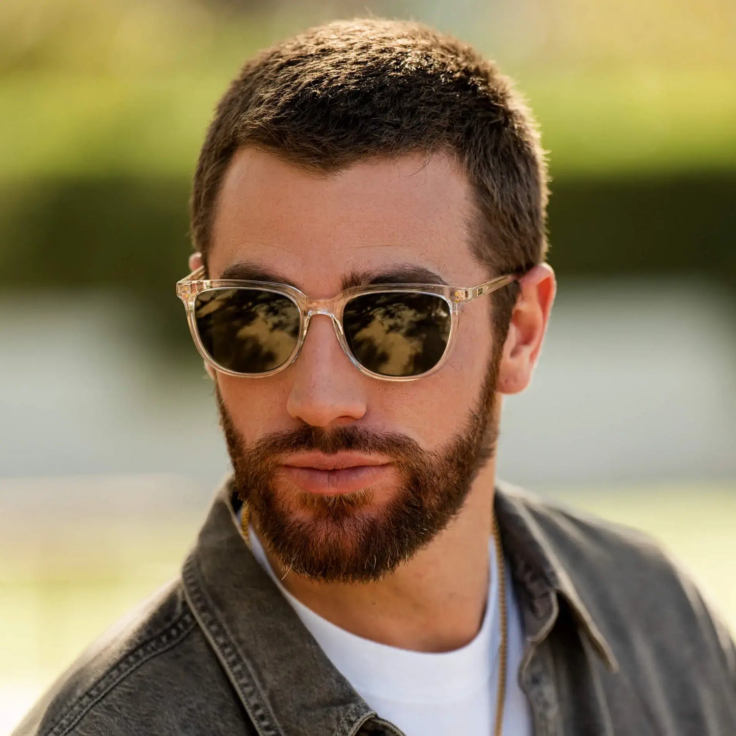 Clear / G15 || Square prescription sunglasses with clear acetate frame, keyhole bridge, and green lenses worn outdoors