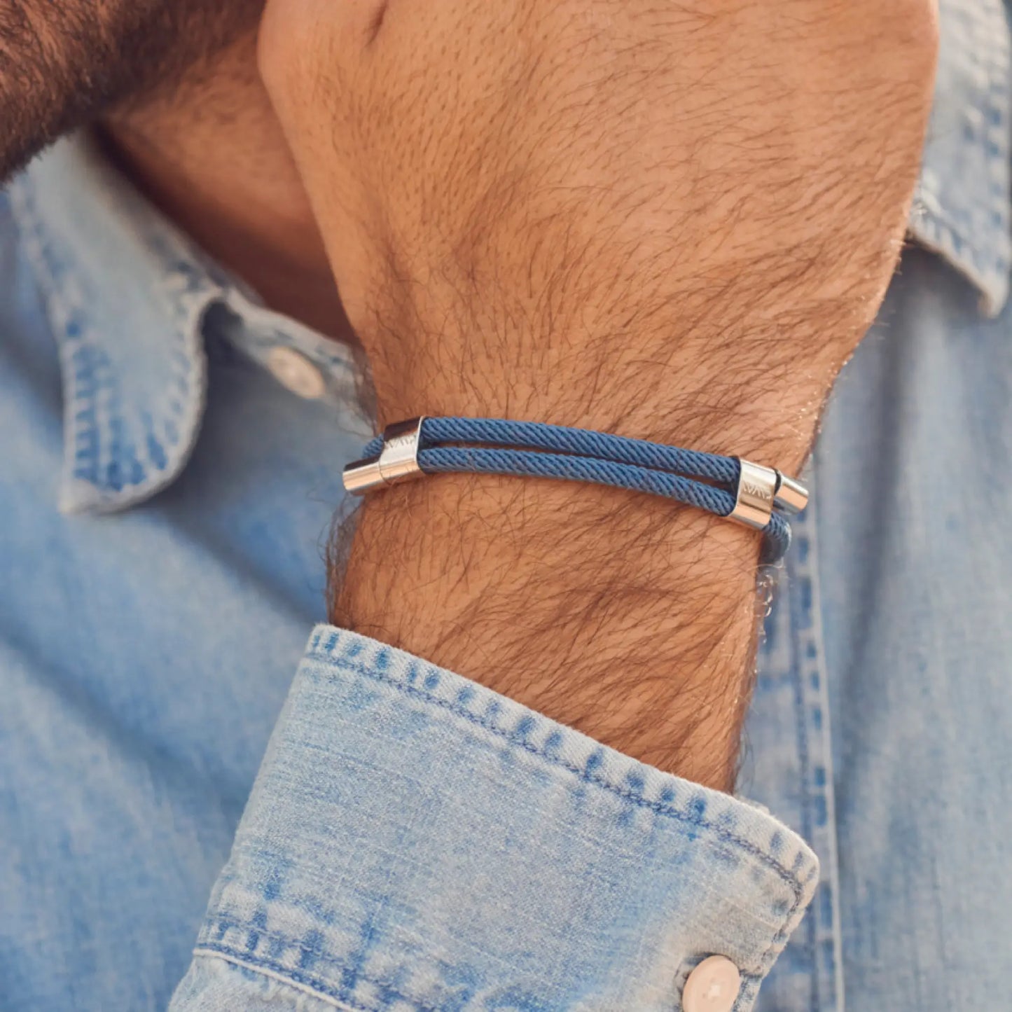 Denim Blue / Silver || Blue twisted rope bracelet with polished silver clasp worn on wrist above light denim shirt cuff