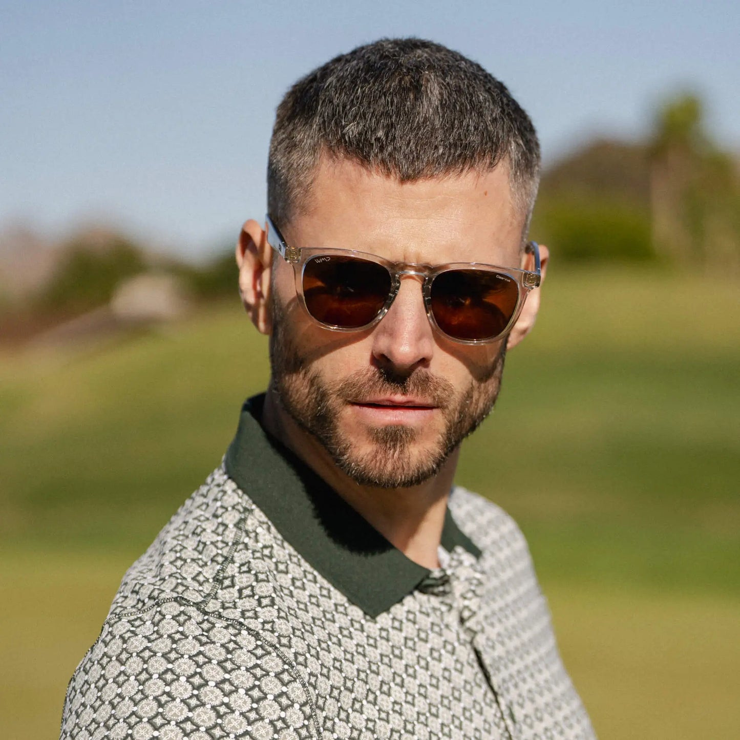 Crystal Ice Grey / Amber || Model wearing Men's Round Prescription Sunglasses with Clear Frame and Brown Lens