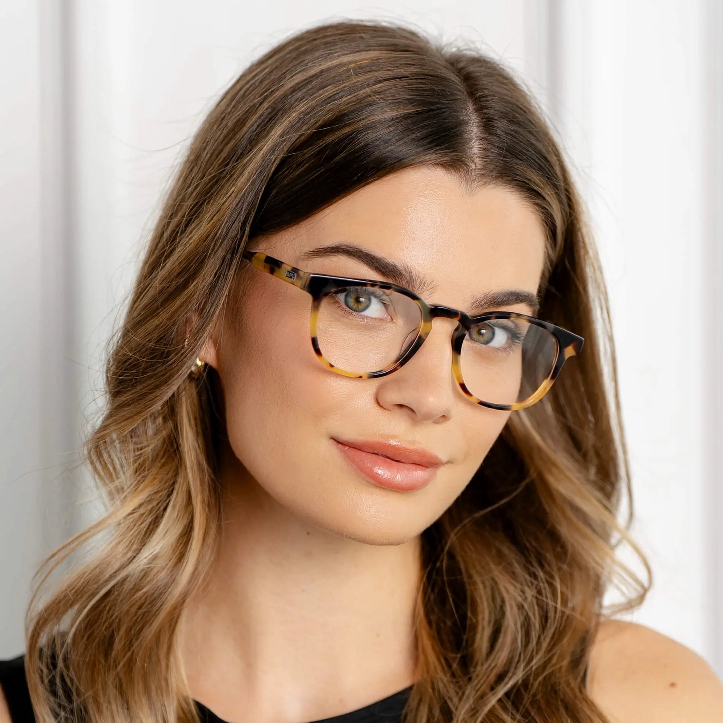 Dune Tortoise || Woman wearing Cal blue light glasses with classic tortoise square frames against neutral background