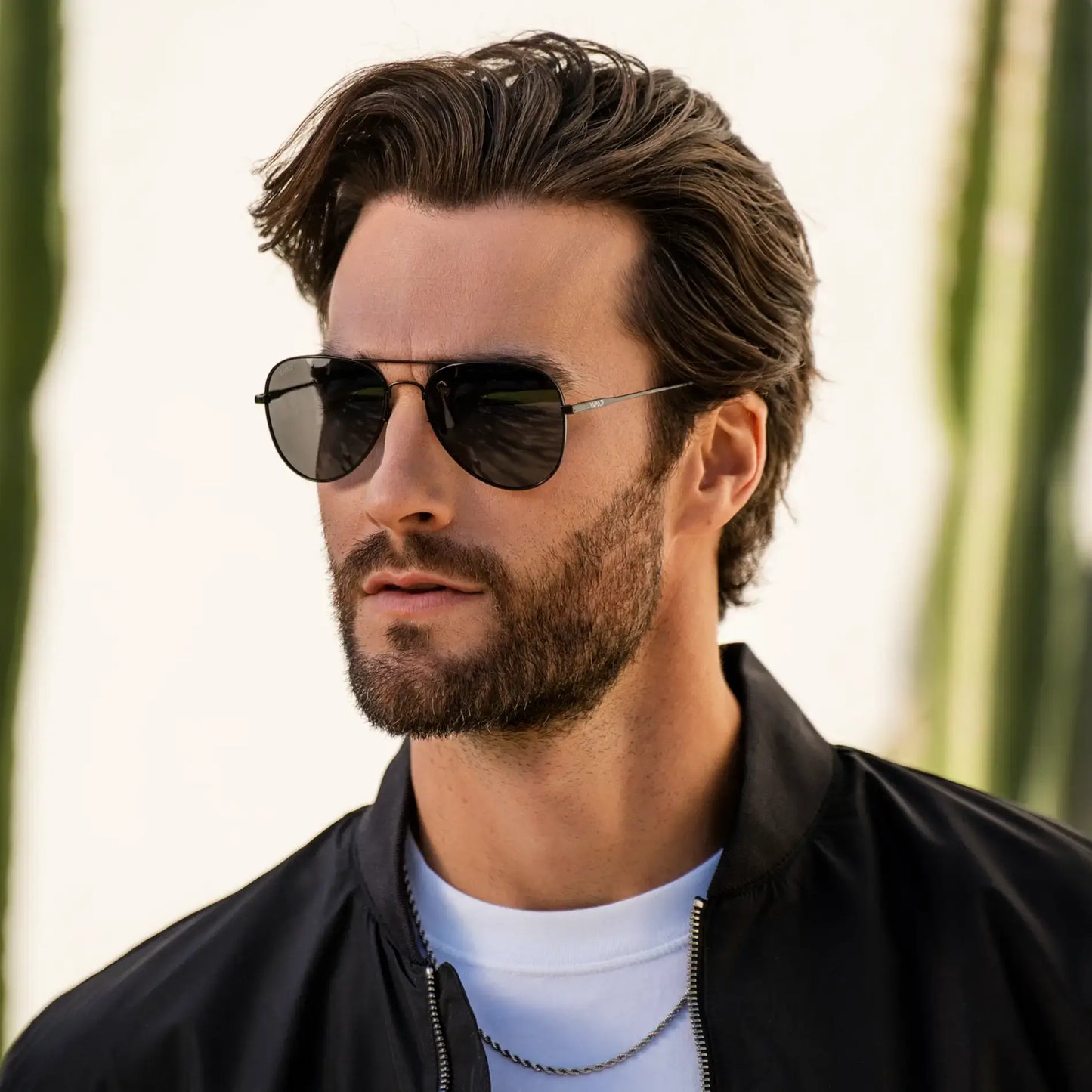 Man wearing slim metal frame aviator sunglasses with polarized lenses outdoors against blurred background