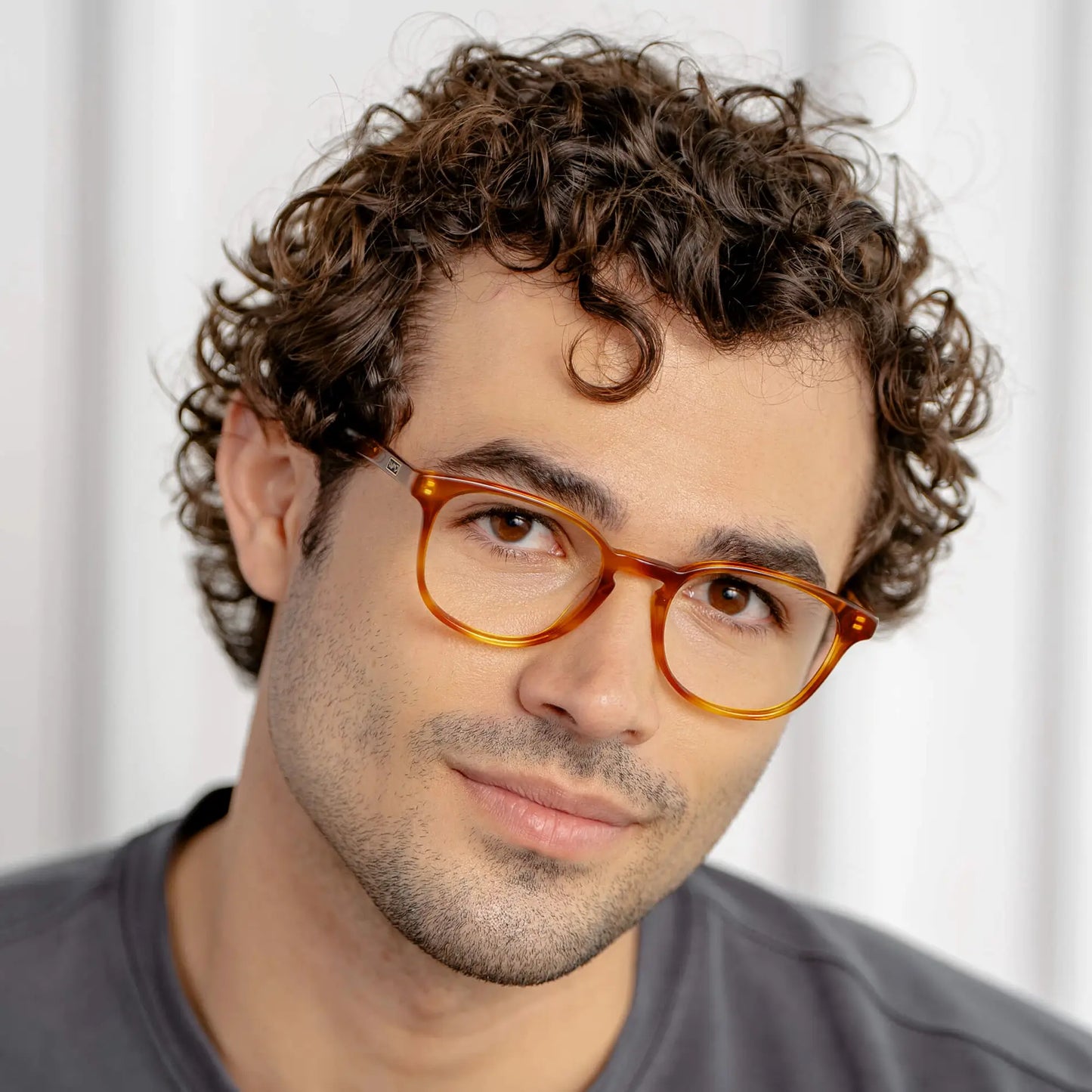 Honey Tortoise || Miles blue light glasses with honey tortoise translucent frames worn by man with curly hair in natural lighting