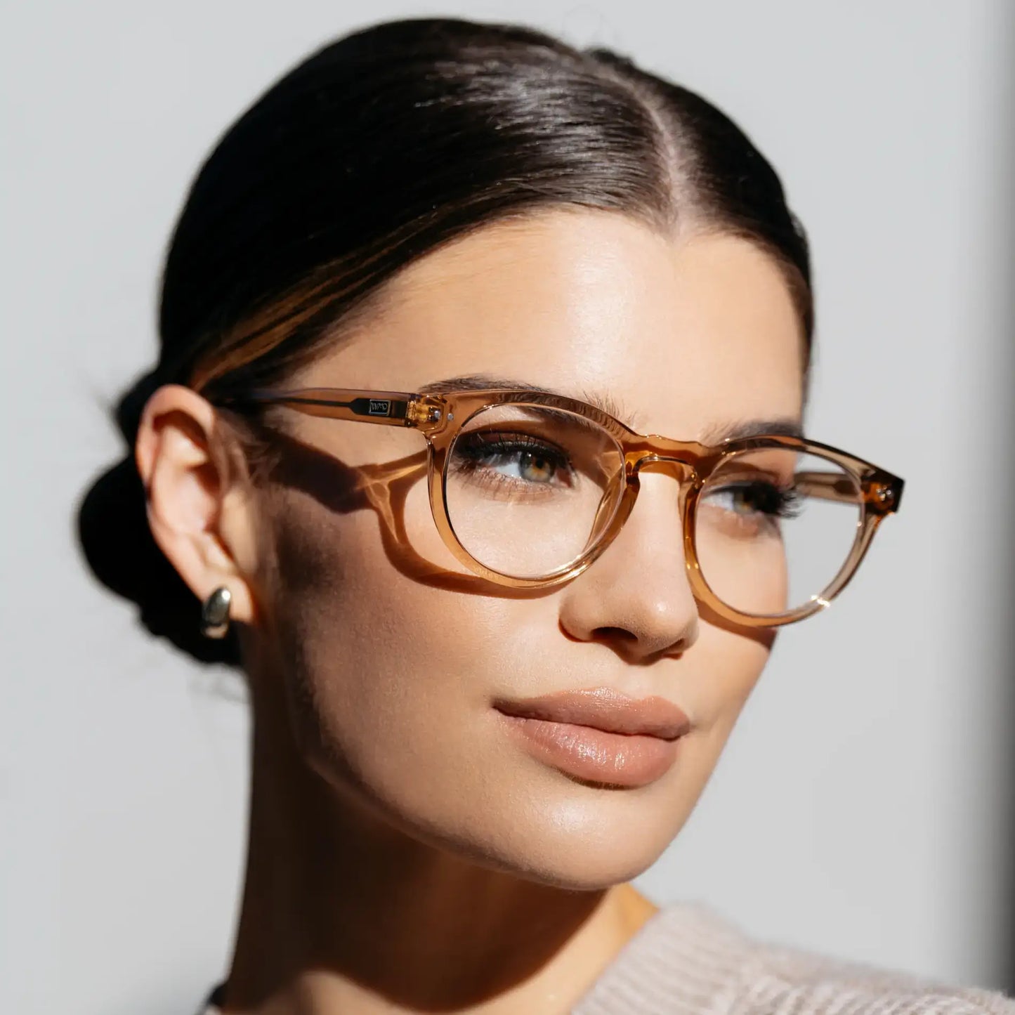Light Crystal Brown || Side profile of round prescription eyeglasses with light brown frame and keyhole bridge worn by woman indoors