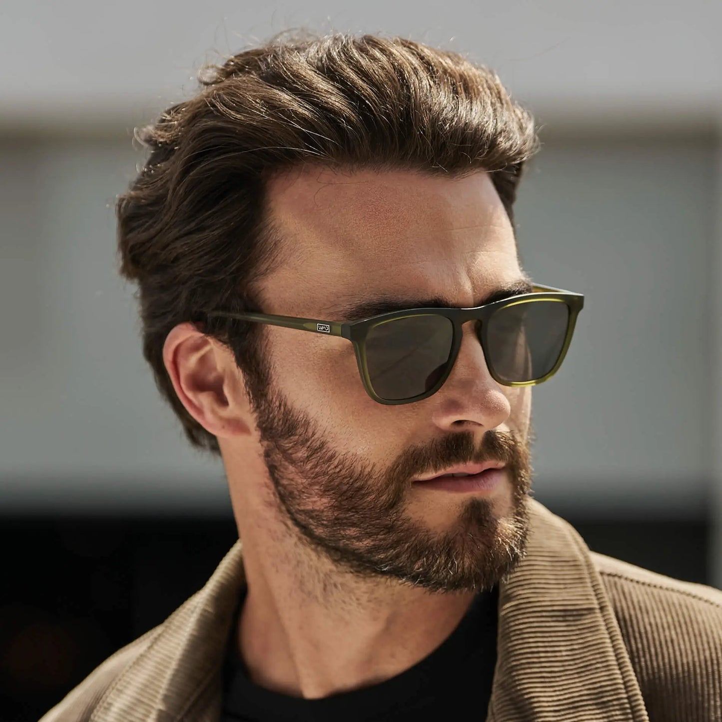 Man wearing sleek square sunglasses with strong browline and notched nose bridge in outdoor setting