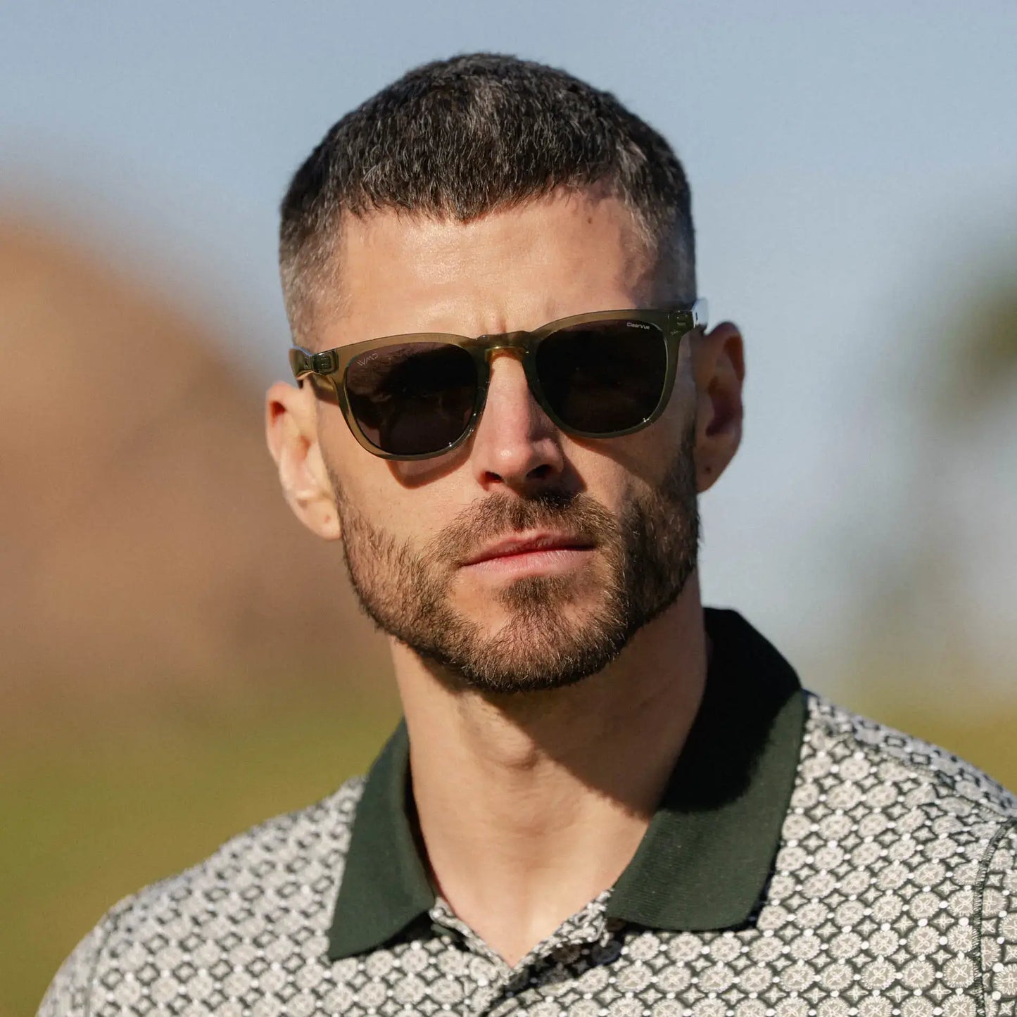 The Pro Kit || Front view of a model outdoors wearing Wyndham men’s golf sunglasses in crystal agave green frame with grey lenses.