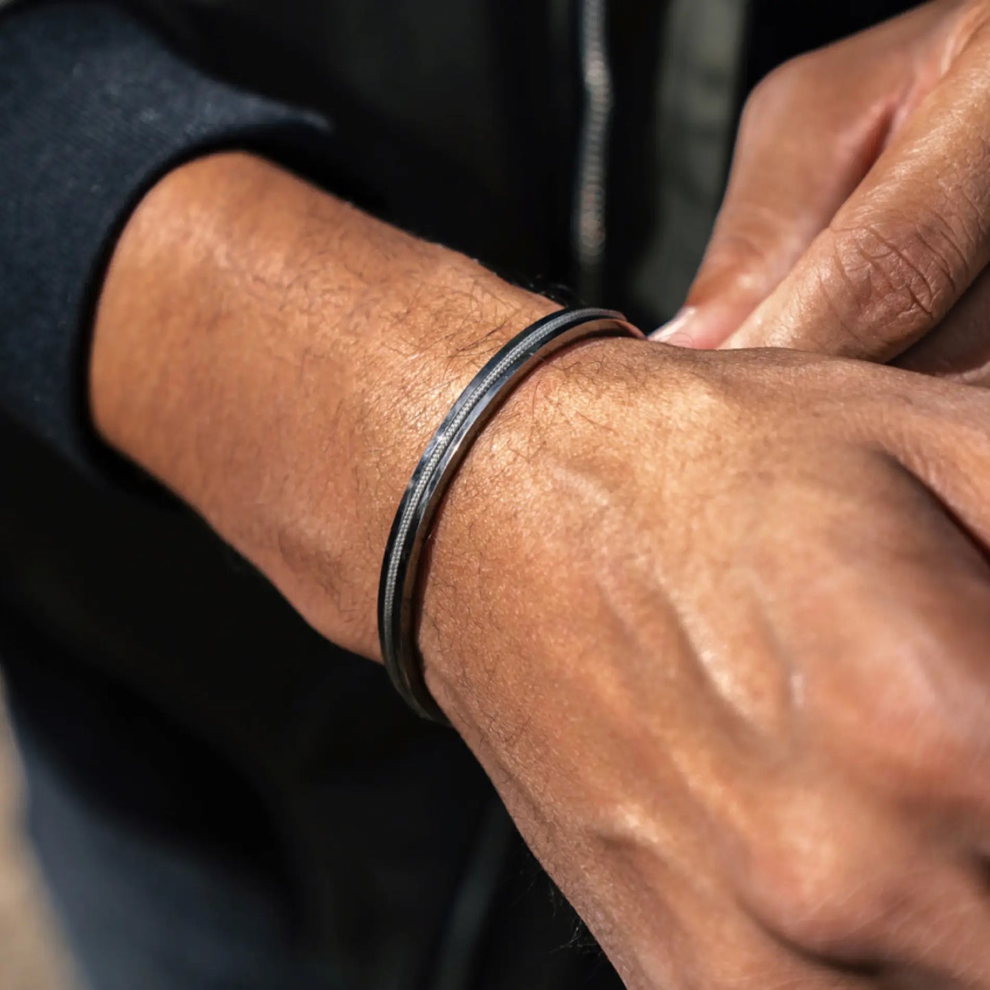 Gunmetal / Olive Green || Close up of a model wearing the Gunmetal Stainless Steel Adjustable Cuff Bracelet with Green Nylon Rope in natural lighting.