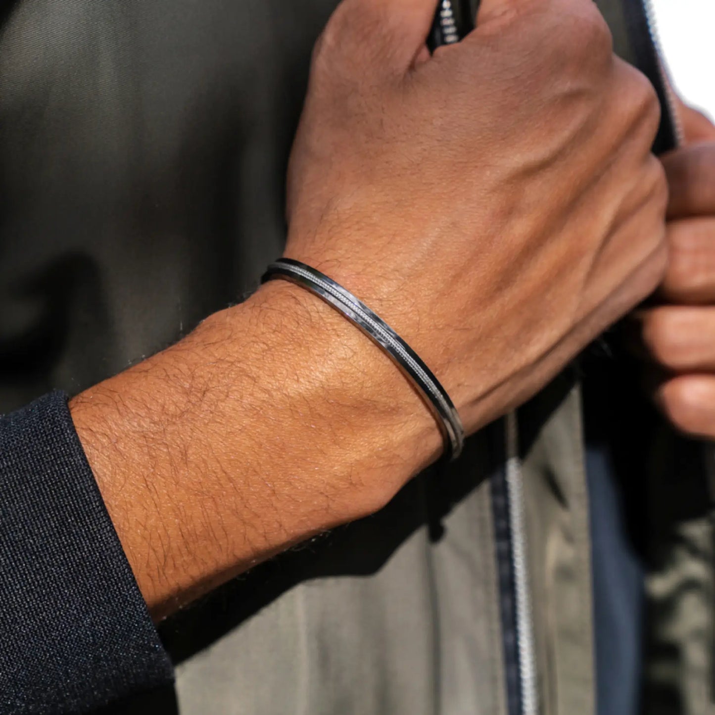 Gunmetal / Olive Green || Close up of a model wearing the Gunmetal Stainless Steel Adjustable Cuff Bracelet with Green Nylon Rope in natural lighting.