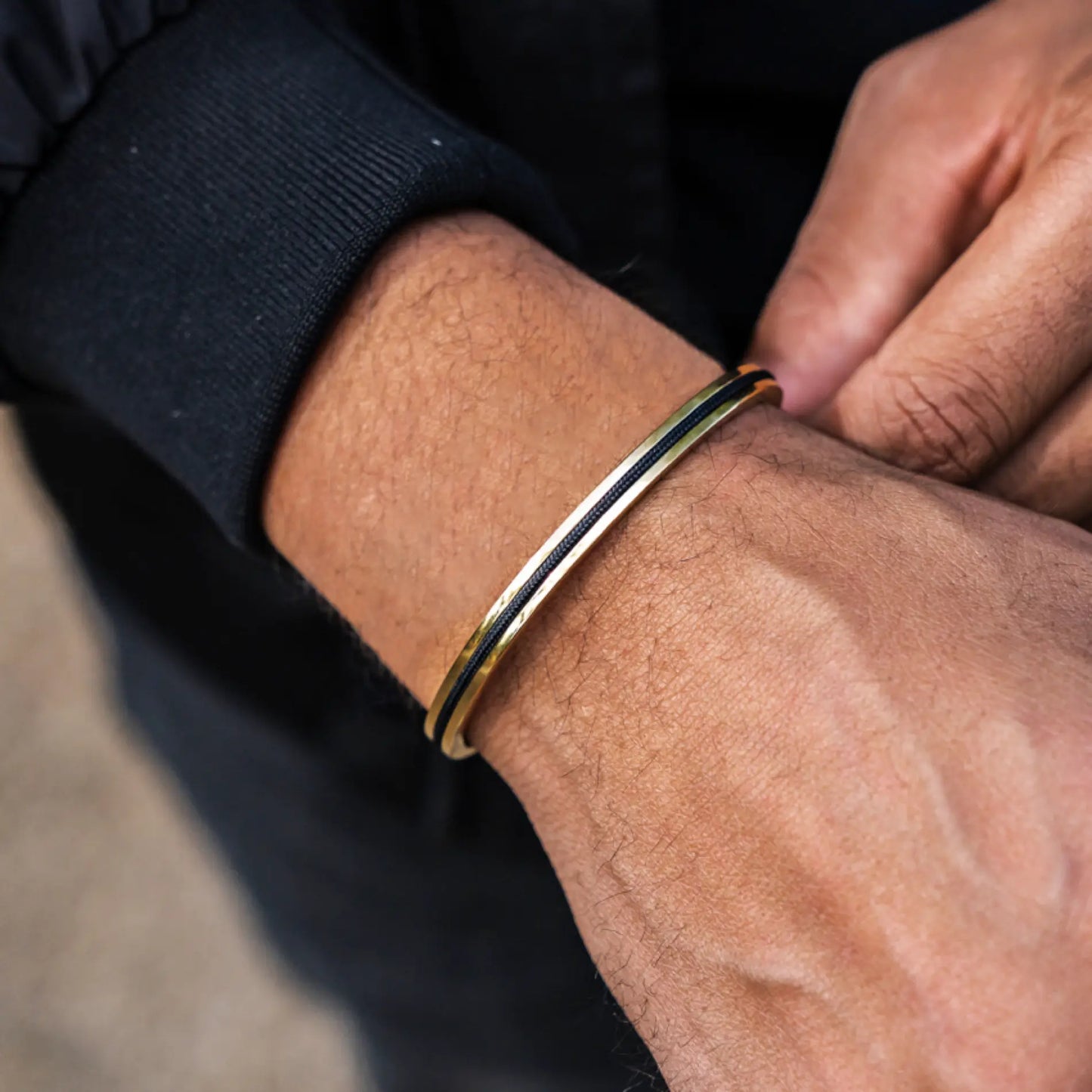 Gold / Onyx Black || Close up of a model wearing the 14K Gold Plated Adjustable Cuff Bracelet with Black Nylon Rope in natural lighting.