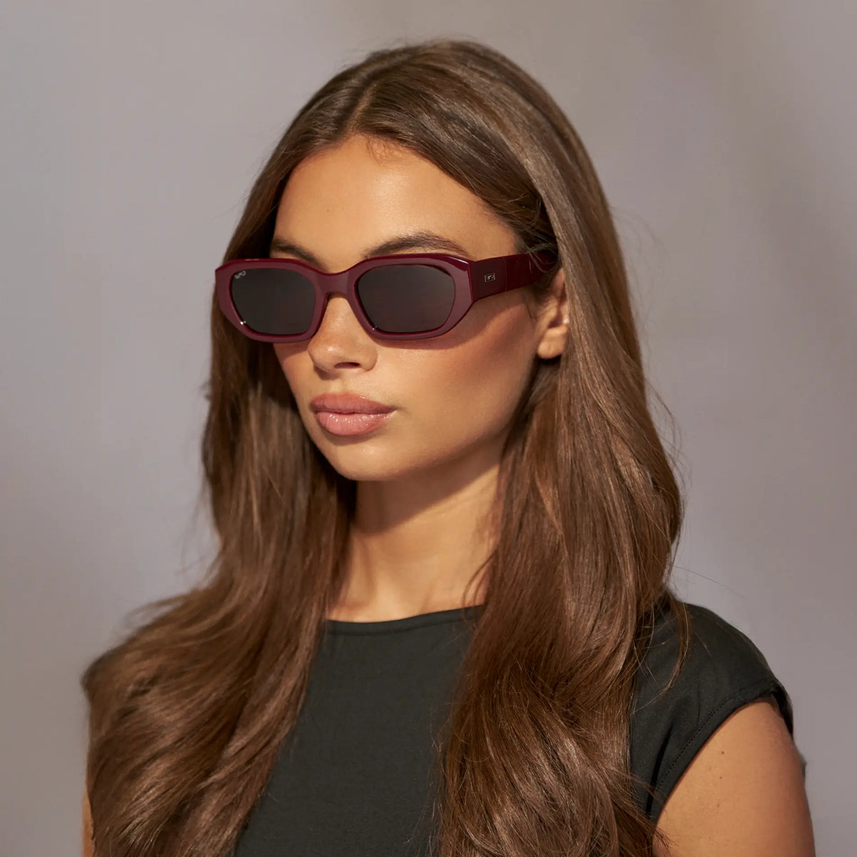 Black Cherry Red / Dark Brown Lens || Side view of Woman wearing Rectangular Cateye Polarized Sunglasses with Red frame and dark brown lens against a grey background
