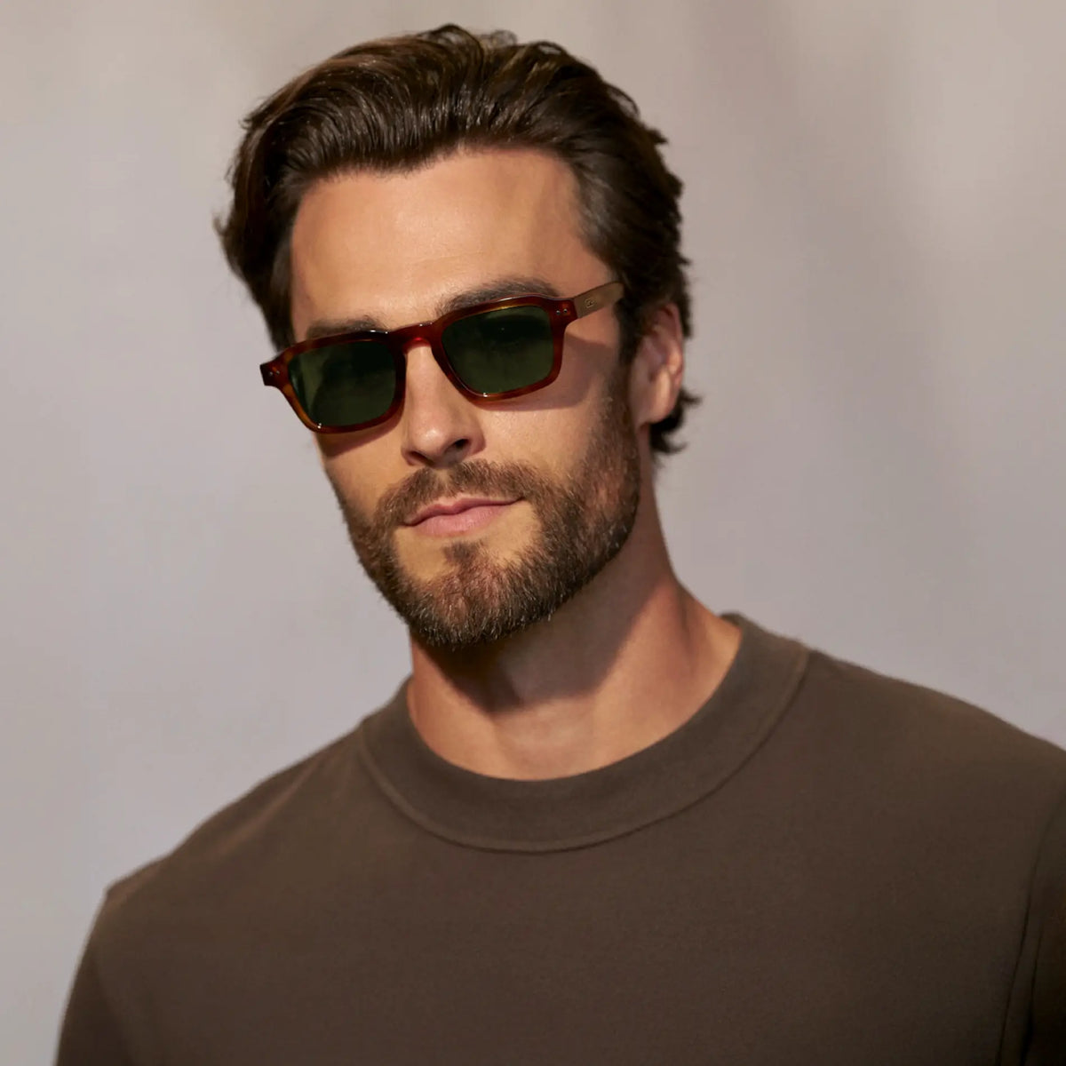 Saddlewood Tortoise / Smoke Green Lens || Front view of man wearing Rectangular Polarized Sunglasses with Saddlewood Tortoise frame and Smoke Green lens against a grey background