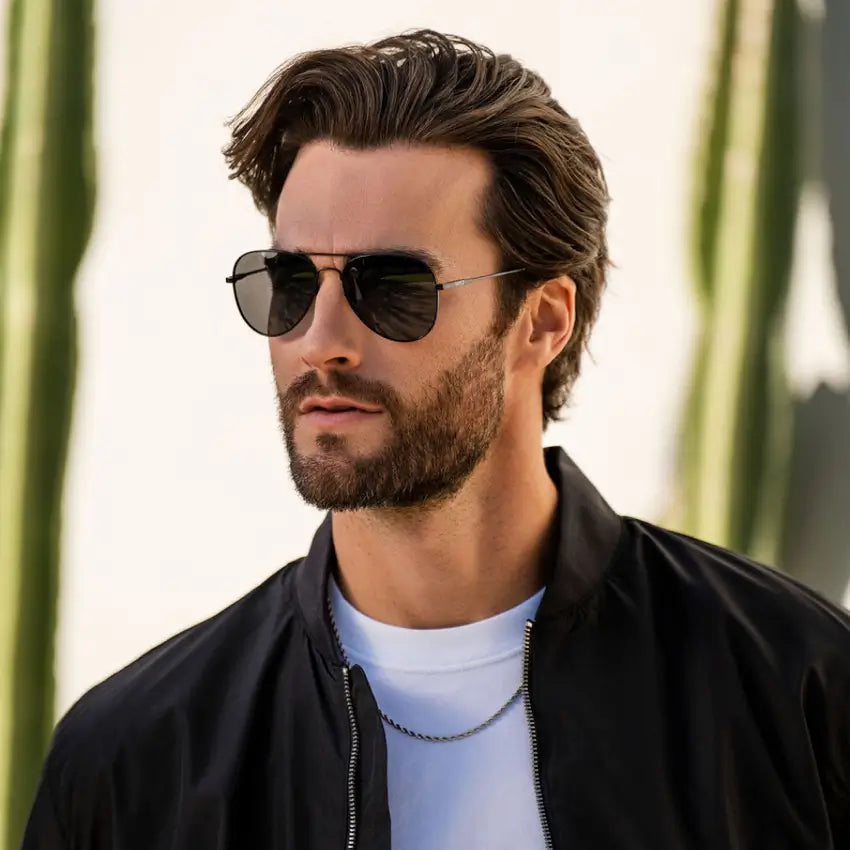 Man wearing classic aviator sunglasses with thin metal frame and dark polarized lenses outdoors