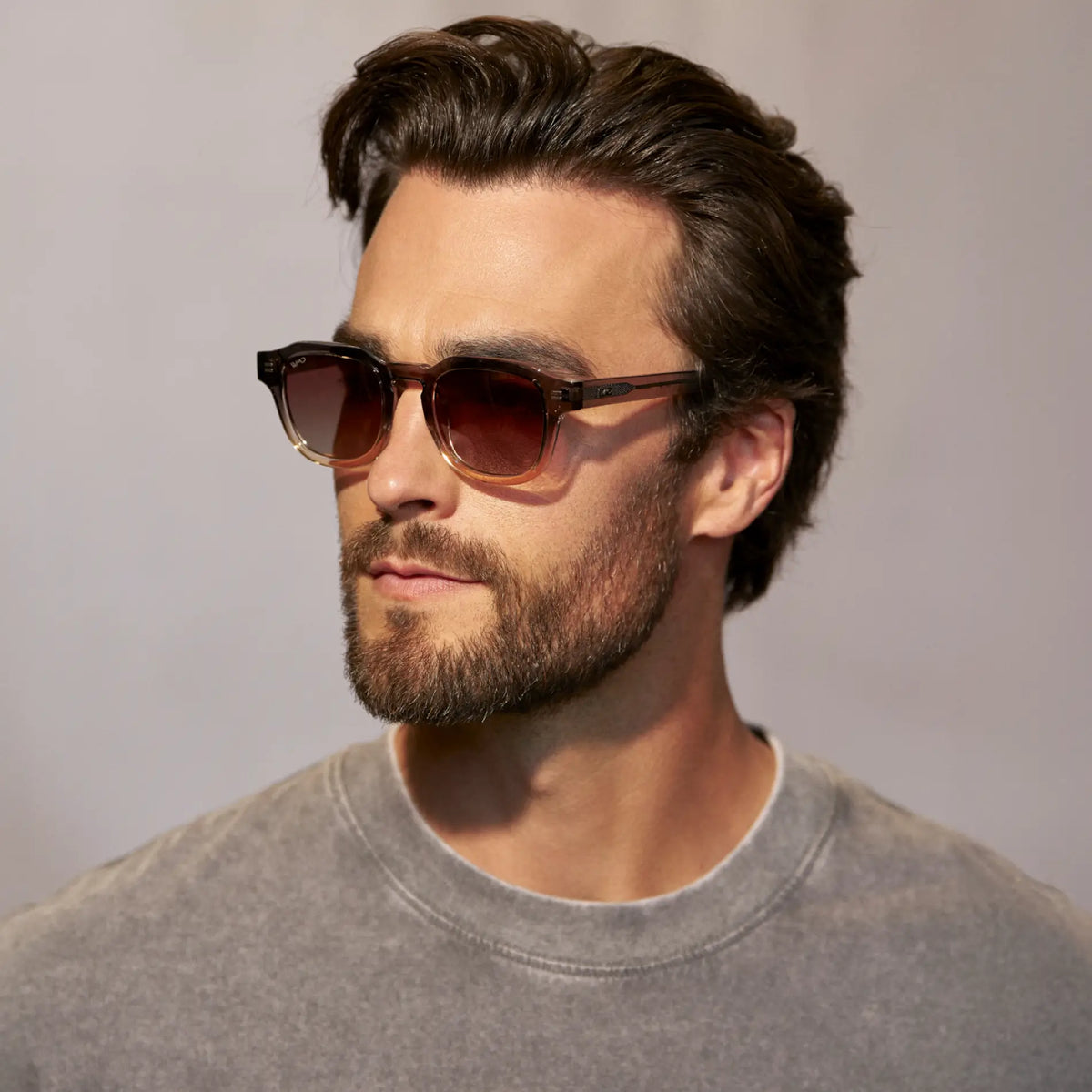 Graphite Horizon Grey / Brown Gradient Lens || Model wearing Men's Geometric Square Polarized Sunglasses with Grey Frame and Brown Gradient lens against a grey background
