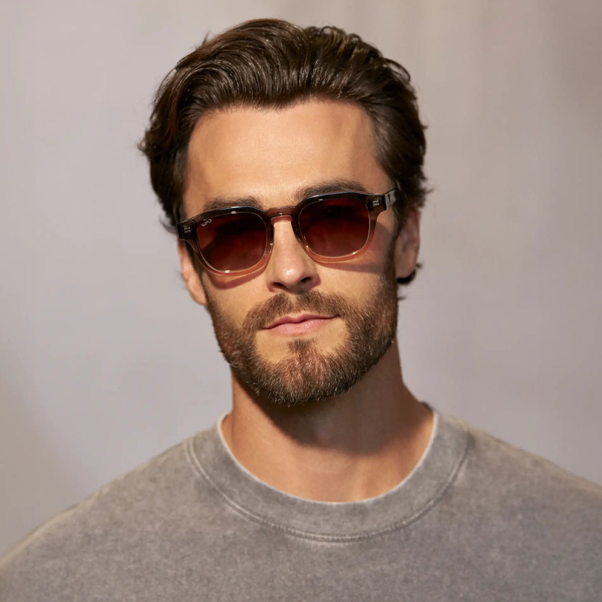 Graphite Horizon Grey / Brown Gradient Lens || Model wearing Men's Geometric Square Polarized Sunglasses with Grey Frame and Brown Gradient lens against a grey background