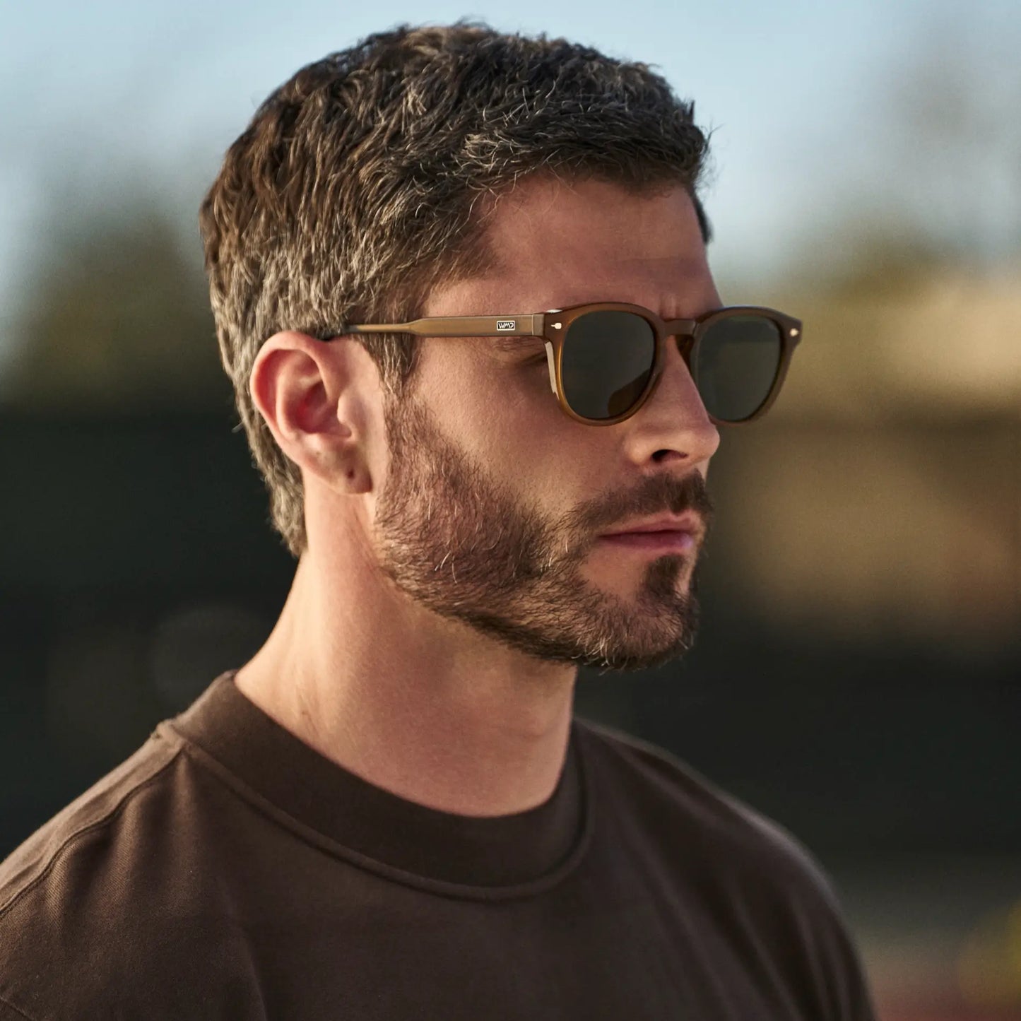 Dune Brown / Smoke Green Lens || Man wearing Round Sunglasses with Dune Brown Frame and Smoke Green Oval Lens in natural light