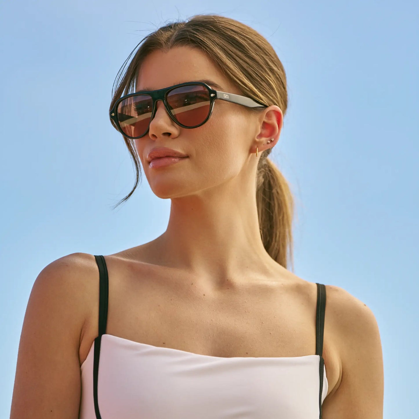 Black / Tinted Red Lens || Woman wearing Rounded Aviator Sunglasses with Black Frame and Red Tinted Lenses outdoors