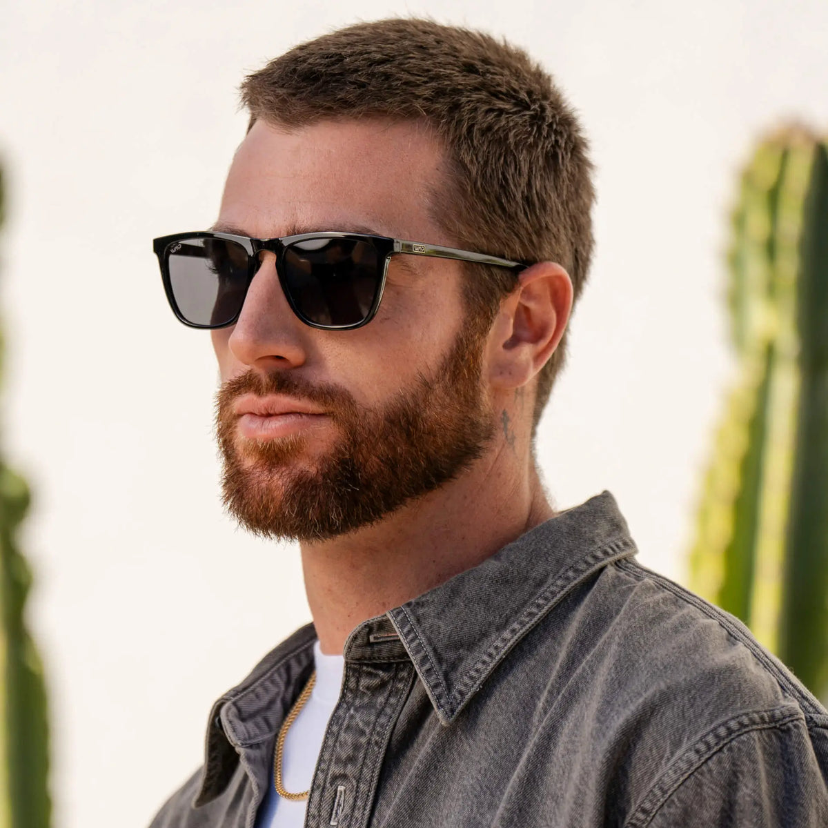 Man wearing sleek square sunglasses with strong browline and notched nose bridge in outdoor setting