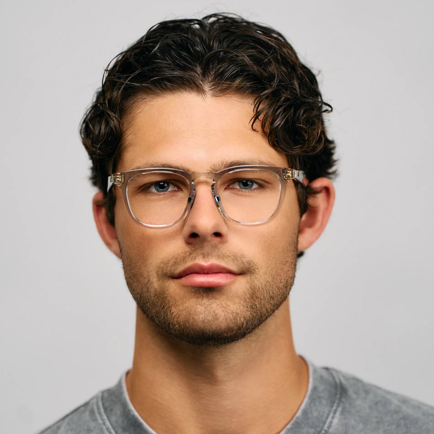 Crystal Ice Grey || Round prescription glasses with translucent grey acetate frame and solid bridge worn by man indoors