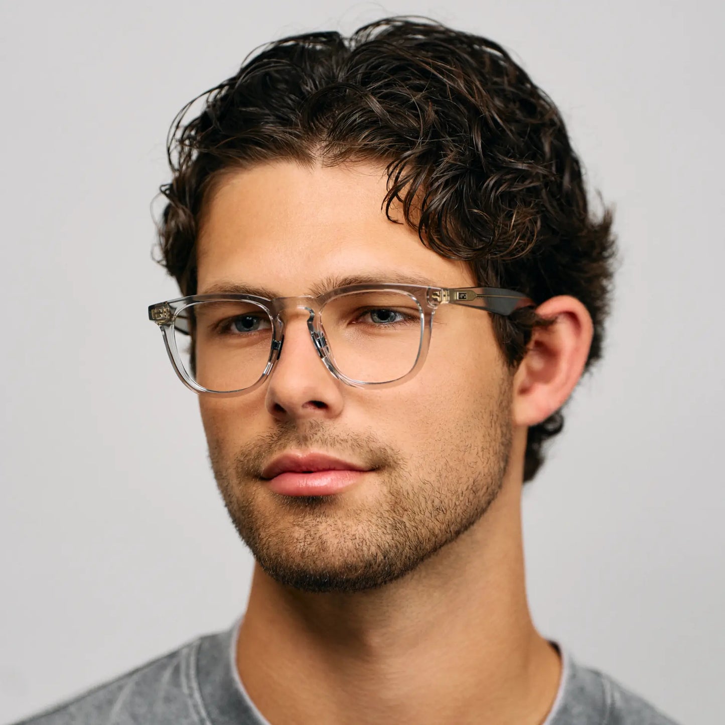 Crystal Ice Grey || Modern round prescription glasses with translucent grey frame and solid bridge worn by man indoors