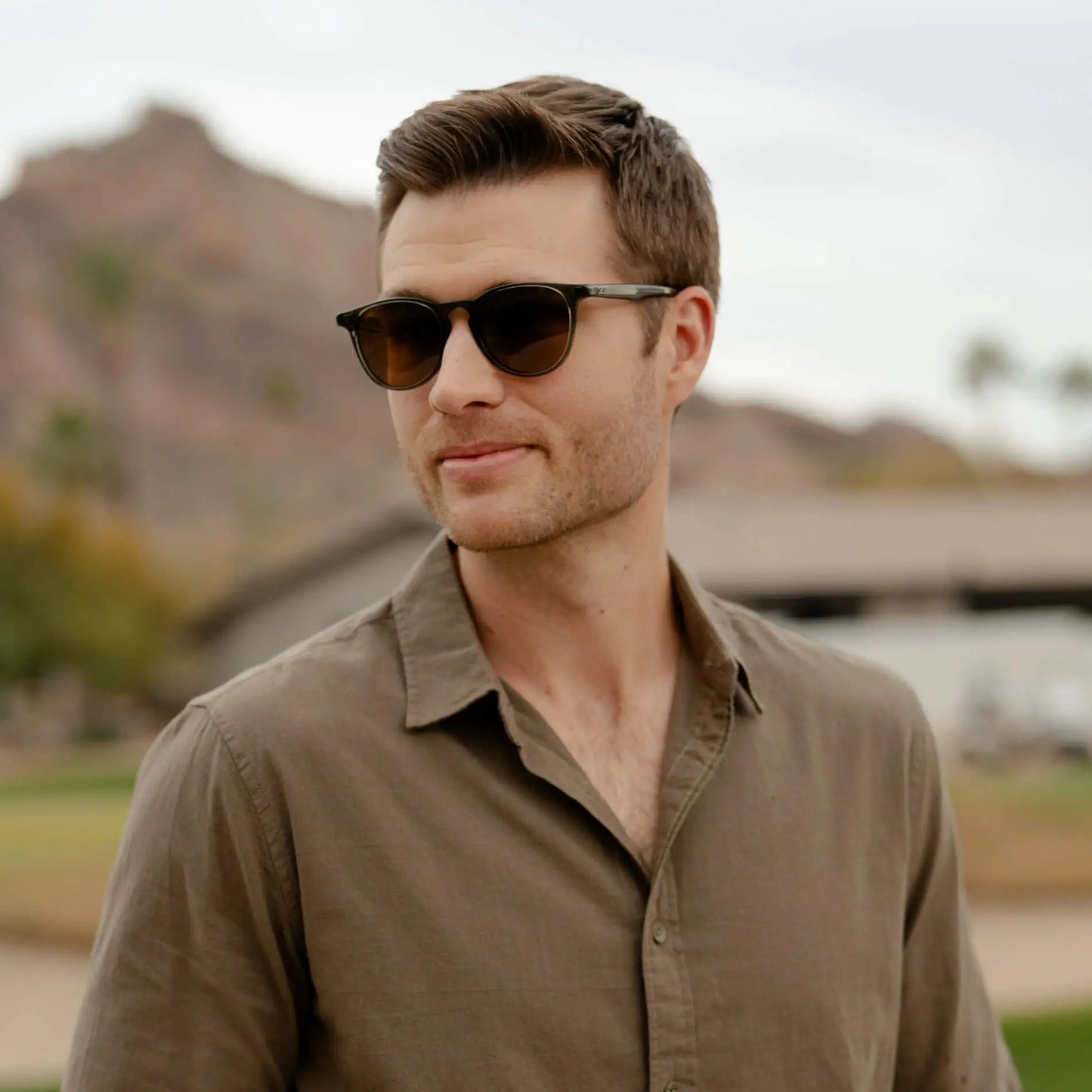 Man wearing Rowan polarized sunglasses with round frames and keyhole bridge outdoors in casual shirt