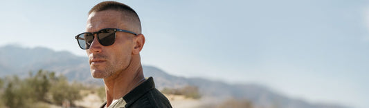 Man wearing sunglasses outdoors with mountains in the background