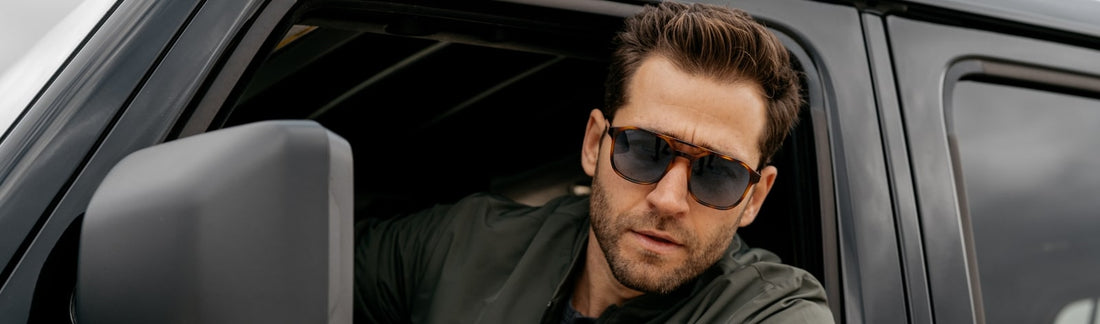 Man wearing dark sunglasses looking out of a vehicle in natural light