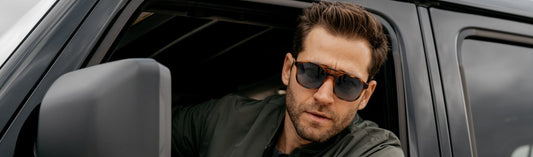 Man wearing dark sunglasses looking out of a vehicle in natural light