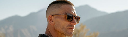 Man wearing sunglasses outdoors with mountains in the background
