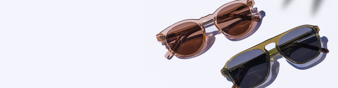 Two pairs of sunglasses arranged on a bright surface in natural light.