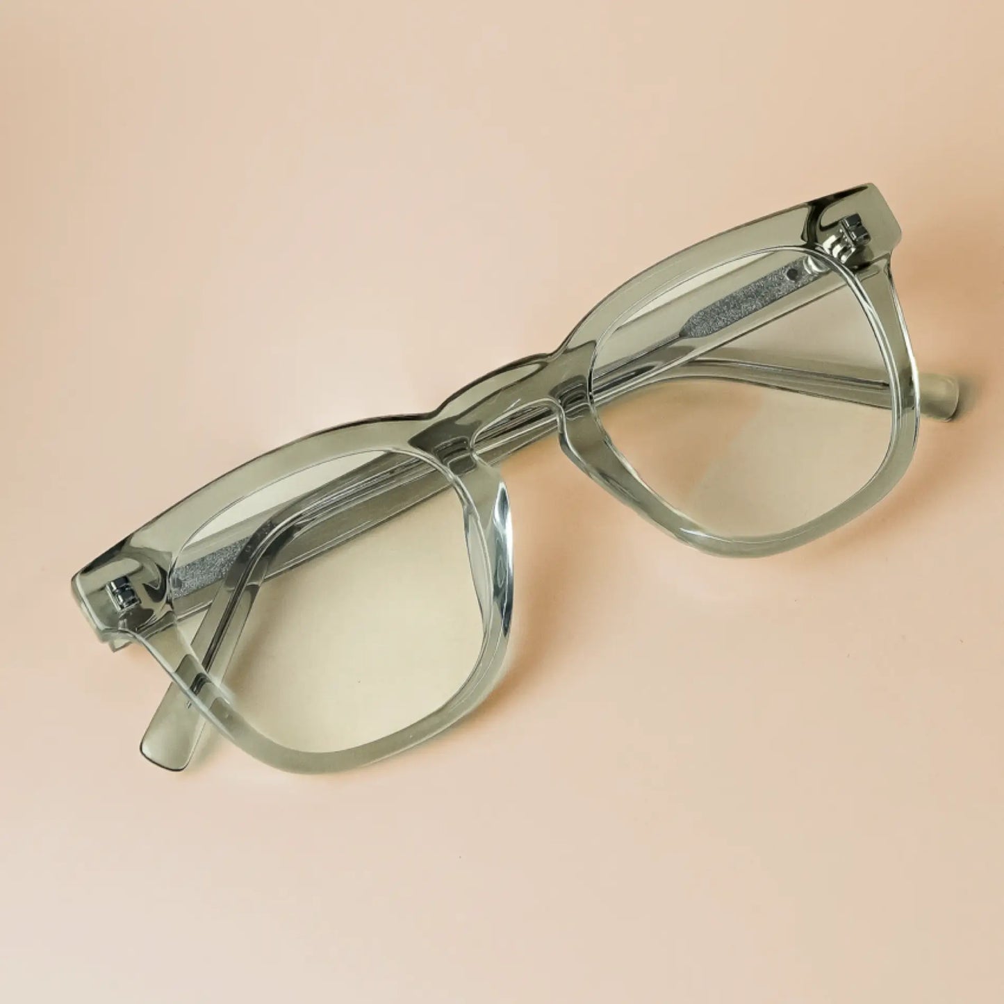 Sea Salt Grey || Aspen translucent light green square frame glasses with clear lenses placed on beige surface