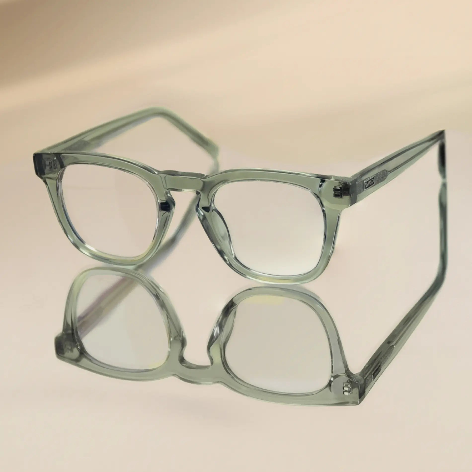 Sea Salt Grey || Aspen green translucent rectangular frame blue light glasses with clear lenses on reflective surface