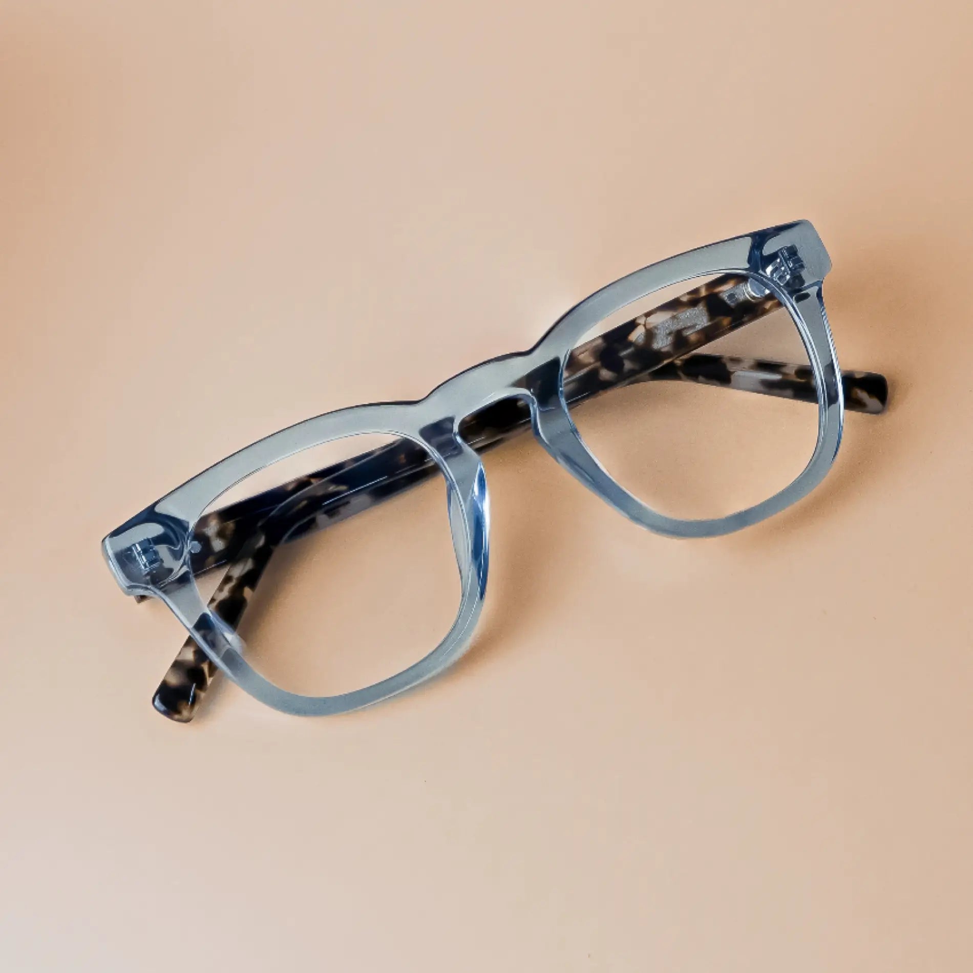 Tortoise Denim Blue || Aspen translucent light blue square frame glasses with tortoise print temples and clear blue light lenses on beige surface