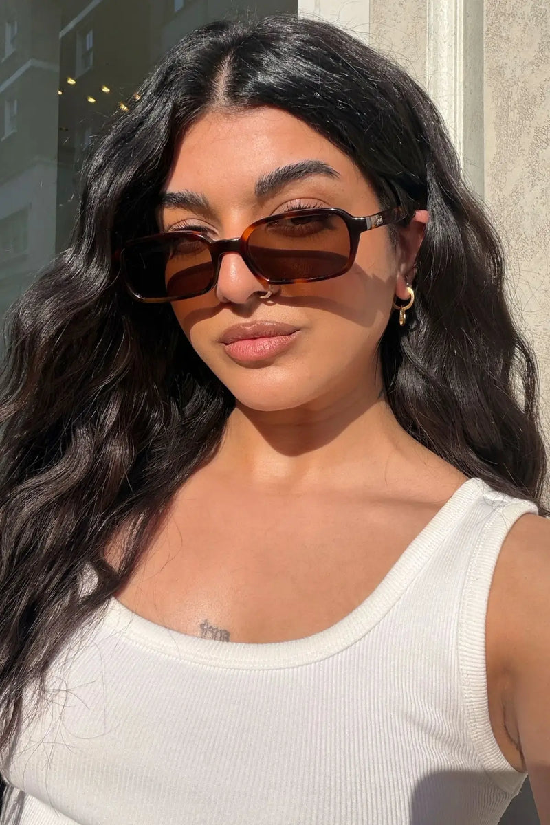 Woman wearing WMP Eyewear narrow rectangular sunglasses in tortoiseshell with brown lenses