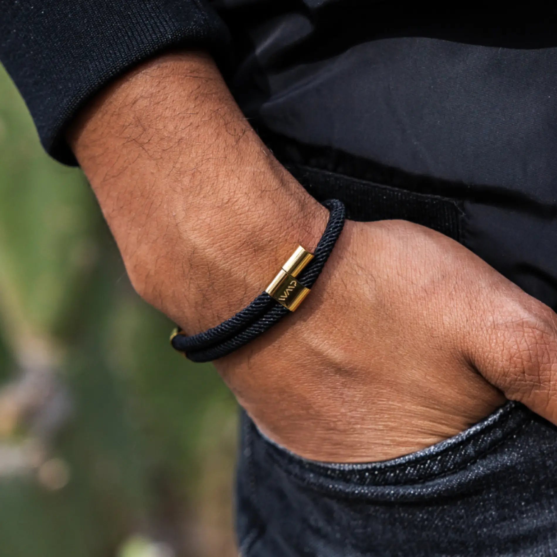 Onyx Black / Gold || Close up of the 14K Gold Plated Adjustable Pull Closure Black Rope Bracelet on a man’s wrist outdoors