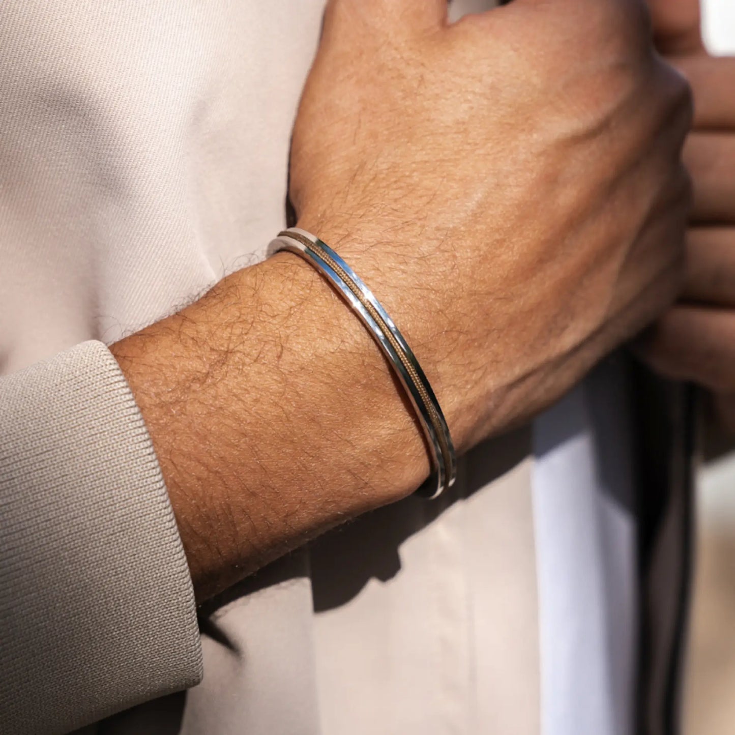 Desert Tan / Silver || Knox & Kent slim polished silver bangle worn on wrist over beige jacket sleeve in natural light