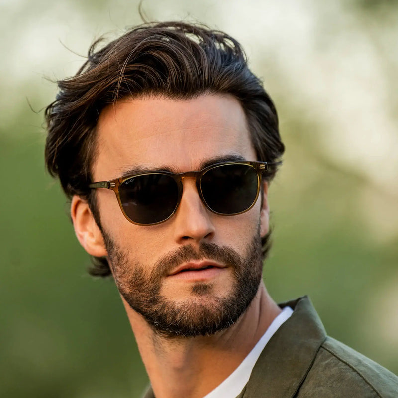Square acetate sunglasses with dark lenses and a keyhole bridge worn by a man outdoors in natural light