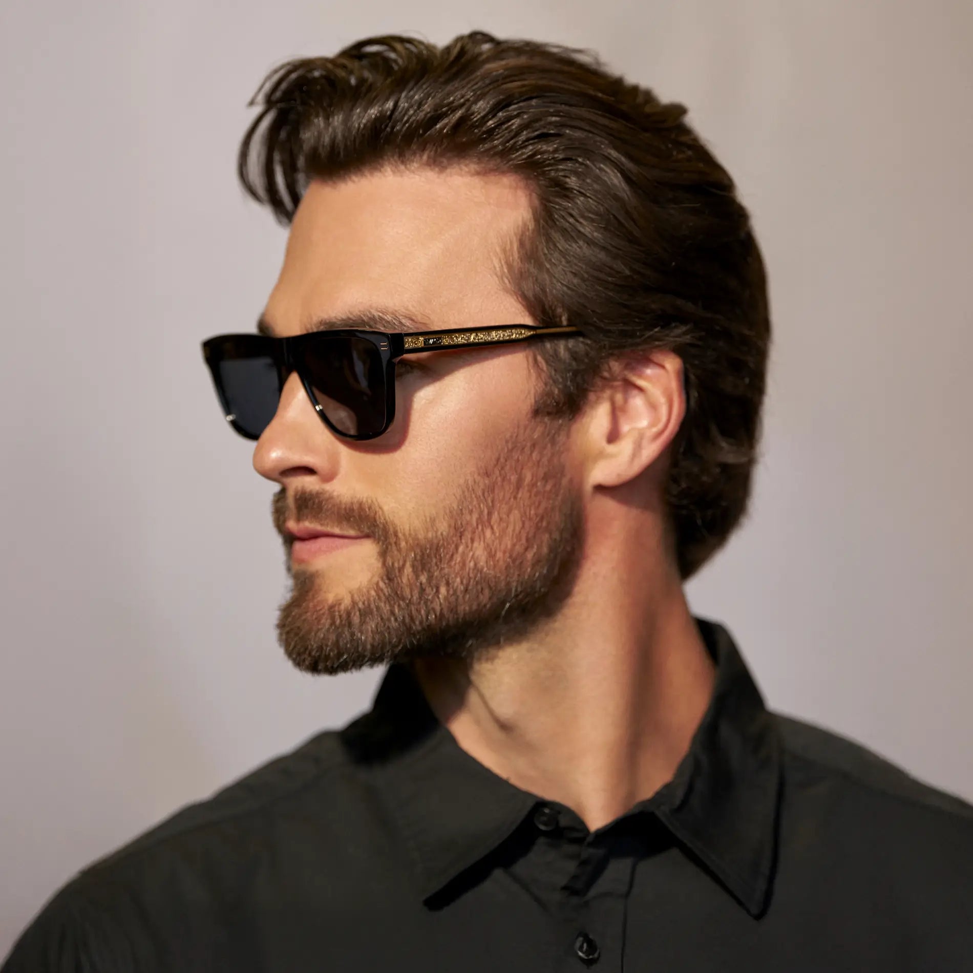 Black / Triple Black Lens || Side view of man wearing Rectangular Polarized Sunglasses with Black Frame and Black Lens against a grey background