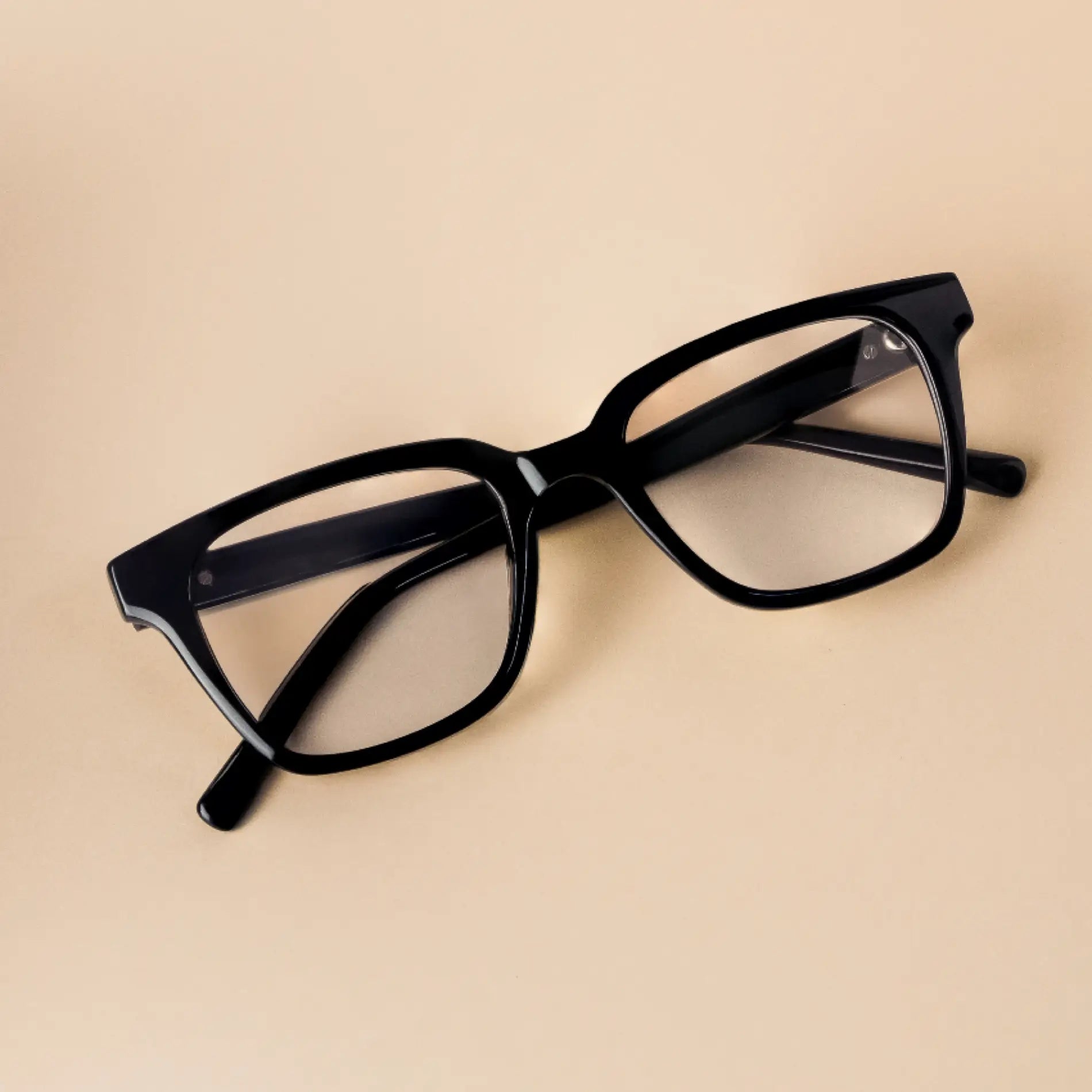 Glossy Black || Black thick rectangular frame blue light glasses resting on beige surface