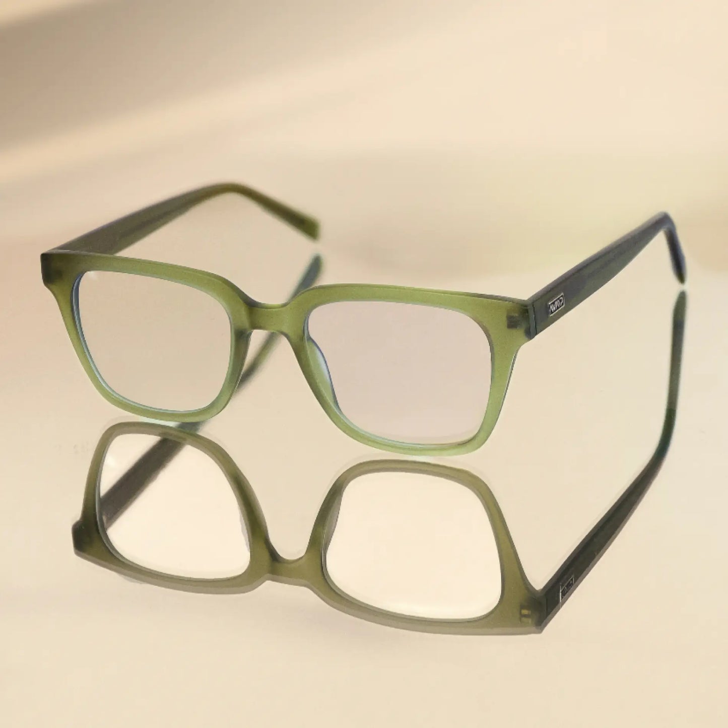Frosted Khaki Green || Modern rectangular prescription glasses with green frame and integrated bridge resting on reflective surface