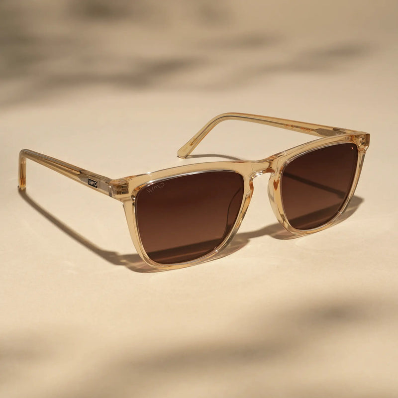 Sand brown round sunglasses with brown lenses against a warm tan background.