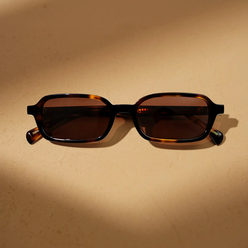 Tortoise rectangular sunglasses with brown lenses on a warm beige background.