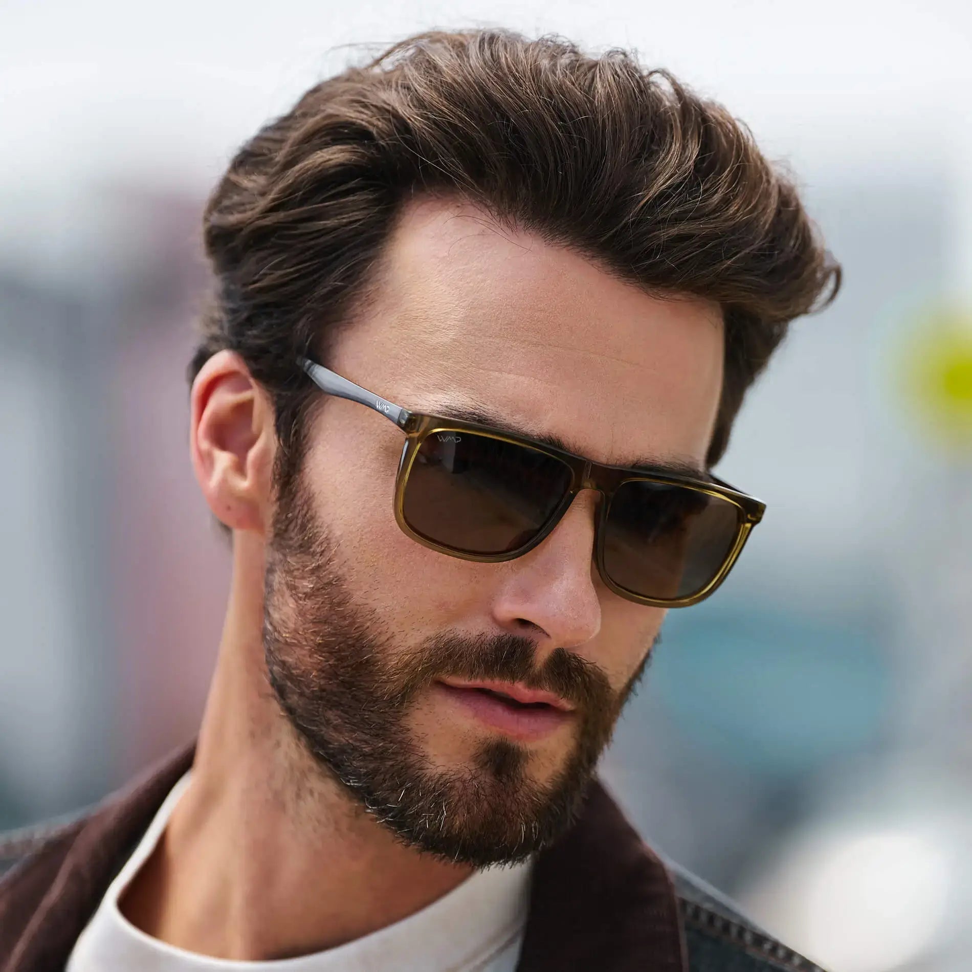 Crystal Verde / Amber || Square prescription sunglasses with crystal verde frame and metal temple accents, featuring a straight browline and amber lenses worn by a man outdoors