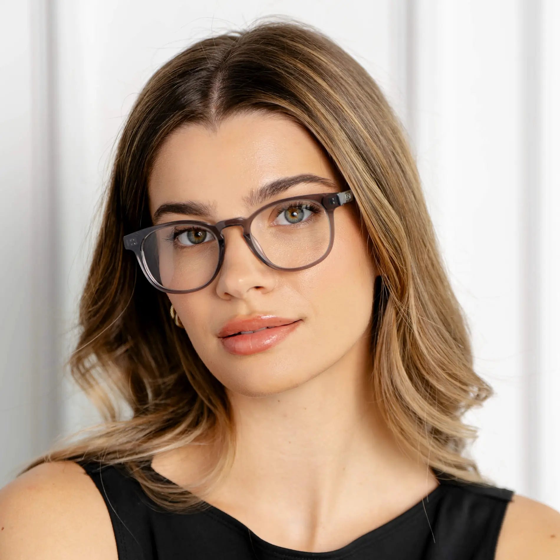 Crystal Grey || Cal blue light glasses with translucent grey square frames worn by woman in natural lighting