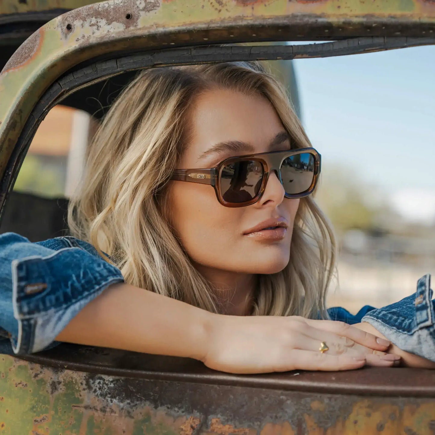 Caramel Brown / Amber || Rectangular prescription sunglasses with thick acetate frames, double bridge, and dark lenses worn by a woman in a vintage truck
