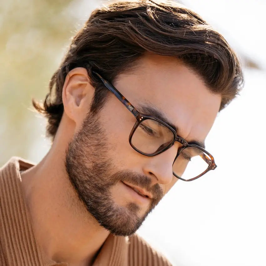 Brown Tortoise || Square prescription glasses with brown tortoise frame and subtle keyhole bridge worn by man looking downward outdoors 