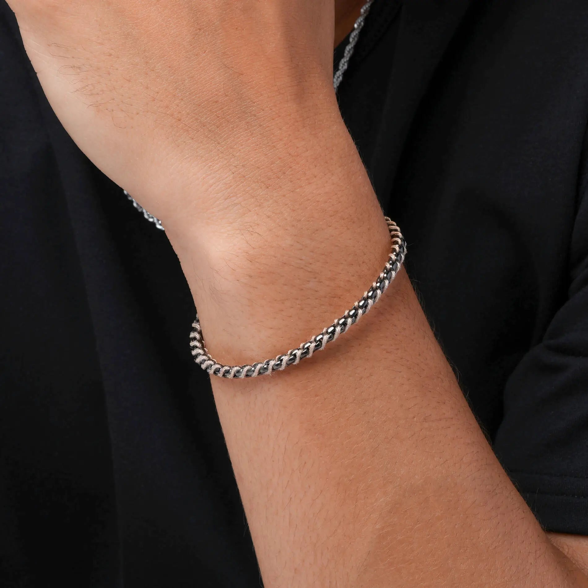 Gunmetal / Sand Rope || Close up of wrist wearing a sleek silver chain bracelet with polished interlocking links on black shirt background